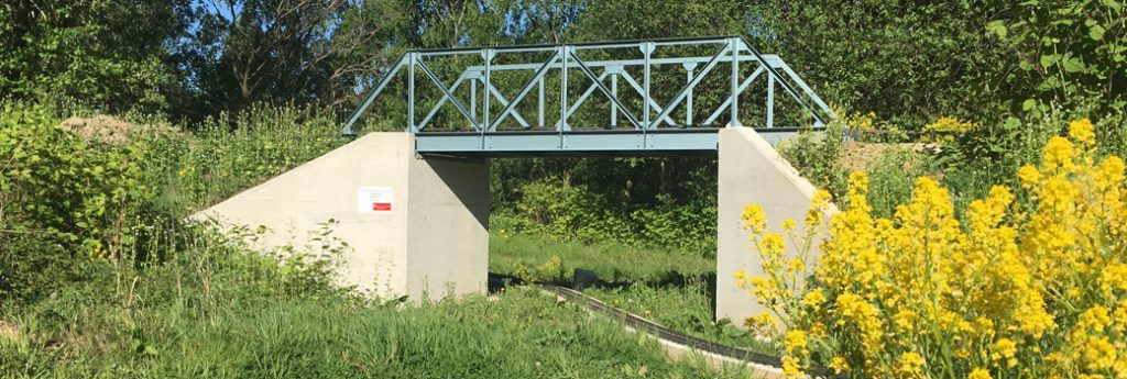 Blau lackierte Brücke als Gleisüberführung  